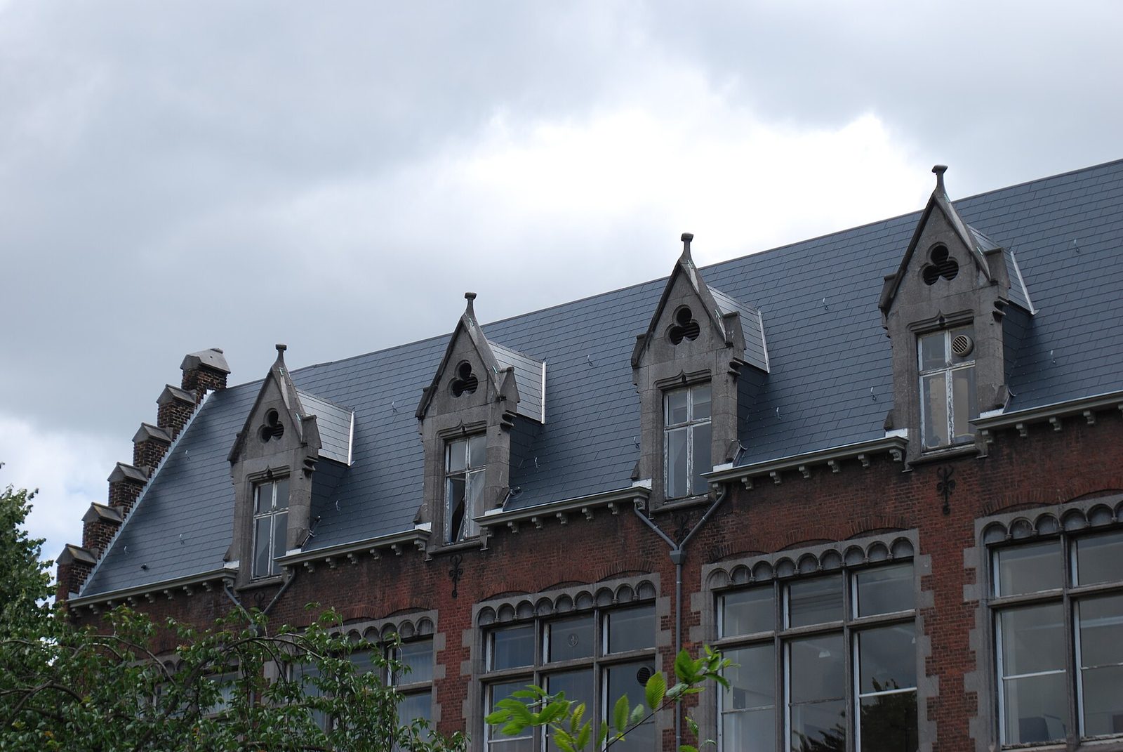 Bakstenen gebouw met een leien dak en een rij dakkapellen